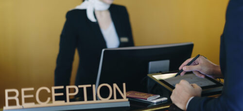 Guest checking in at a sleek hotel reception with helpful staff member